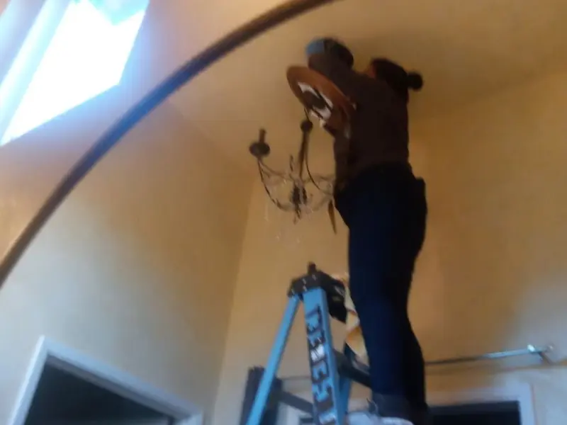 Electrician installing a chandelier in a Minden residence